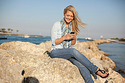 美女,坐,石头,发短信,手机,海滩,棕榈海滩,佛罗里达,美国
