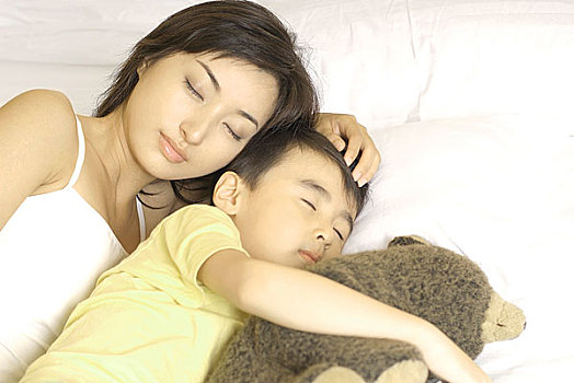 熟睡中的小男孩抱着熊和妈妈