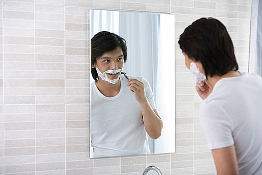 一个男人对着镜子刮胡子