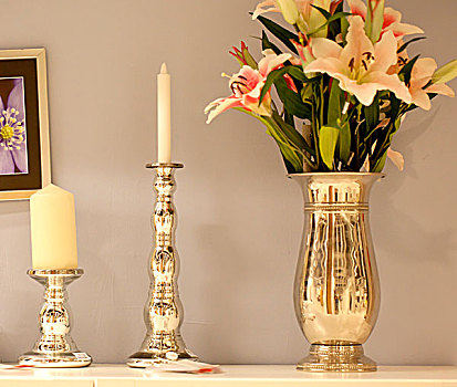 两个蜡烛台插着白色的蜡烛和一盆花并排放置