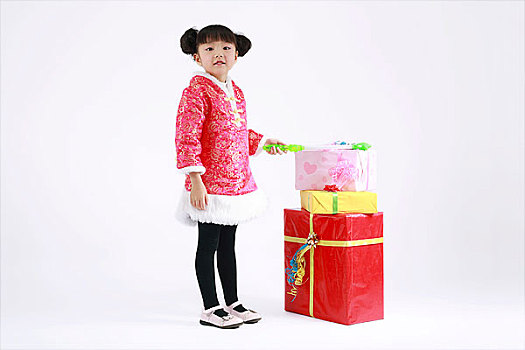 站在一堆礼品盒旁手拿魔法棒的小女孩