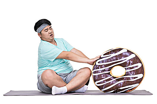 肥胖的青年男子拿着甜甜圈
