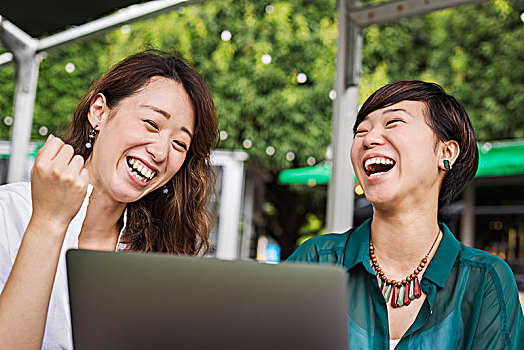 两个女人,黑发,穿,绿色,白衬衫,坐,正面,笔记本电脑,桌子,街头咖啡馆,笑