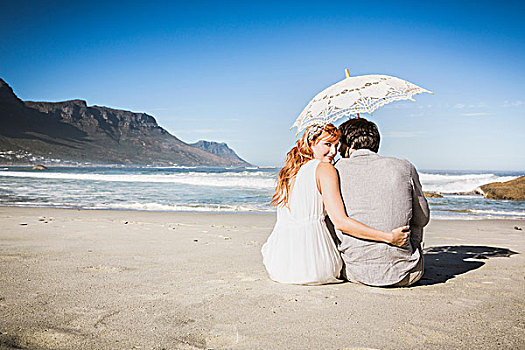 后视图,女人,搂抱,男人,坐,海滩,拿着,伞,扭头,看镜头