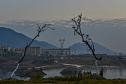 树,两颗树,输电塔,房屋,炊烟,截流,拖拉机,汽车,推土机,池塘,河流,两岸,高压线,高压塔,电力,黄昏,清洁能源,绿色电力