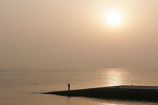山东青岛下午海边孤独钓鱼的人