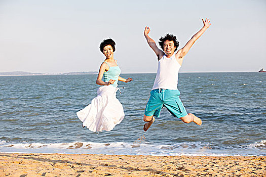 情侣在沙滩跳跃