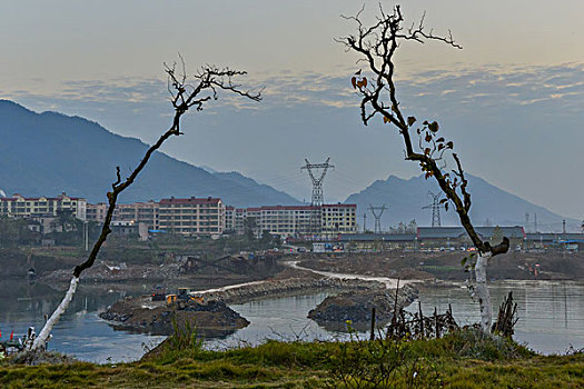 树,两颗树,输电塔,房屋,炊烟,截流,拖拉机,汽车,推土机,池塘,河流,两岸,高压线,高压塔,电力,黄昏,清洁能源,绿色电力