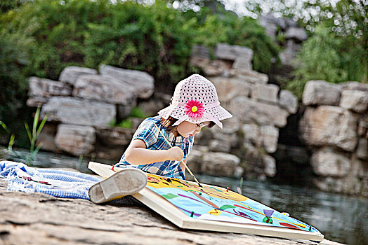 正在河边画画的小女孩