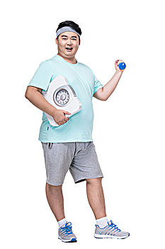 肥胖的年轻男子拿着体重秤健身
