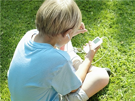 金发,男孩,7-9岁,坐,草,听,mp3播放器,后视图,俯视图