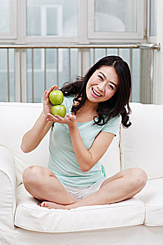 年轻女士坐在沙发上拿着苹果