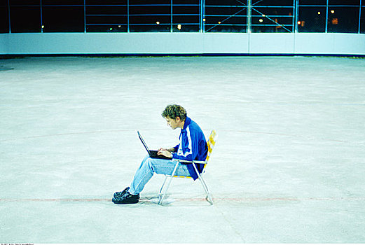 男人,坐,椅子,户外,滑冰场,使用笔记本