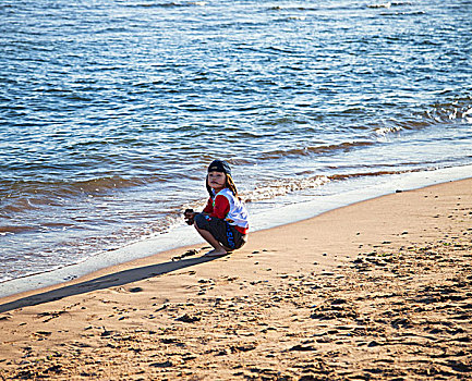 一个可爱的女孩在海边的沙滩上玩耍