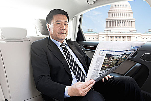 商务男士坐在轿车里看报纸