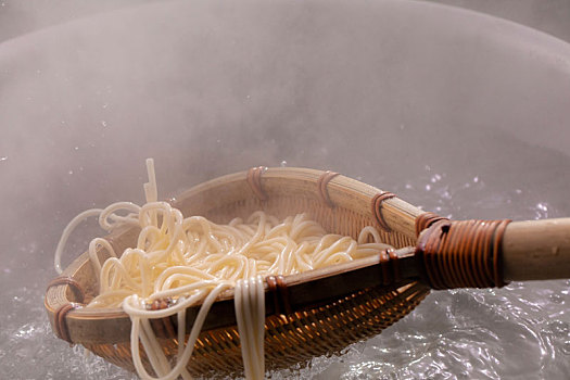 竹箕在大锅中捞起热腾腾的面,面条弹牙有食欲感