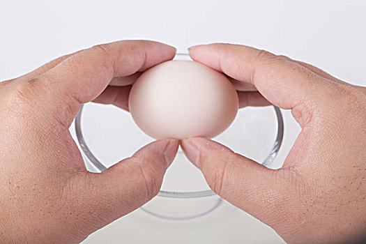 一只手给玻璃碗里打鸡蛋