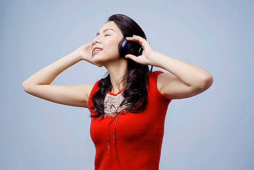 头戴耳机闭着眼睛听音乐的年轻女人