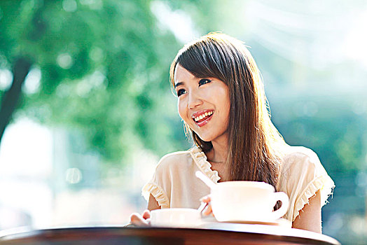 年轻女子在户外咖啡店喝咖啡