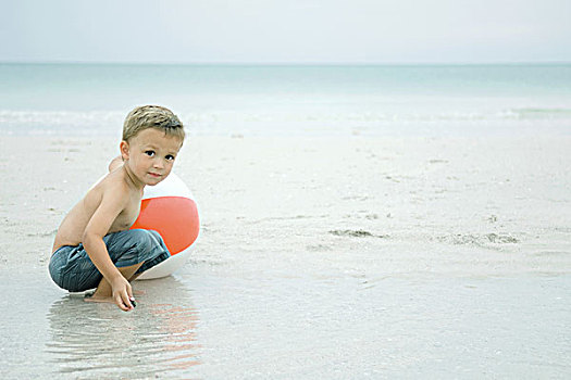 小男孩,蹲,水中,海滩,玩,水皮球,看镜头