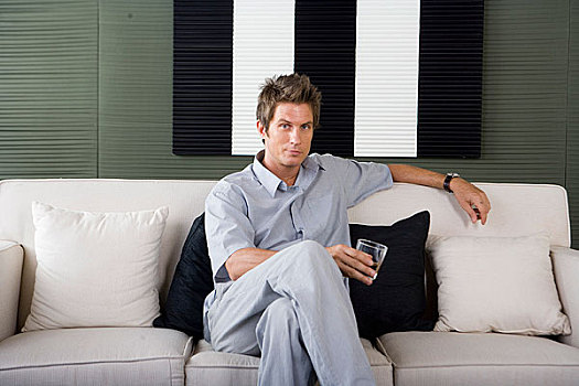 一个穿着休闲装的男人坐在沙发上看着镜头
