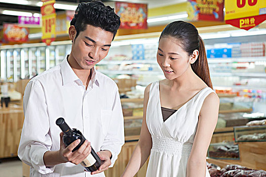 一对年轻夫妇在超市购买红酒