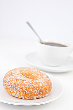 油炸圈饼,糖粉,一杯咖啡,勺子,白色背景,盘子