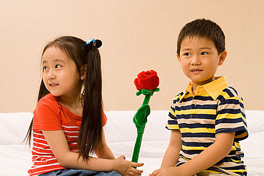 两个小孩举着一支花对着镜头