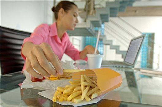 职业女性,吃,炸薯条,使用笔记本