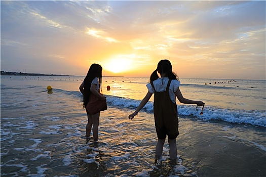 山东省日照市,清晨里的海滩人头攒动,游客赏日出踏浪戏水迎接美好的一天