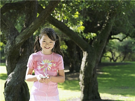 女孩,7-9岁,站立,公园,靠近,树,听,mp3播放器,微笑,正面,头像