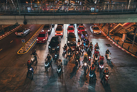泰国曼谷夜晚街道拥挤的车流和等待过十字路口的摩托车