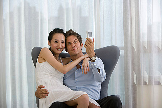 一对夫妻坐在椅子上用手机拍照
