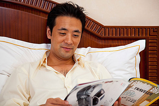 中年男人躺在床上看杂志