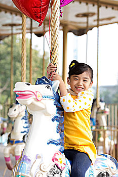 小女孩在游乐园骑旋转木马