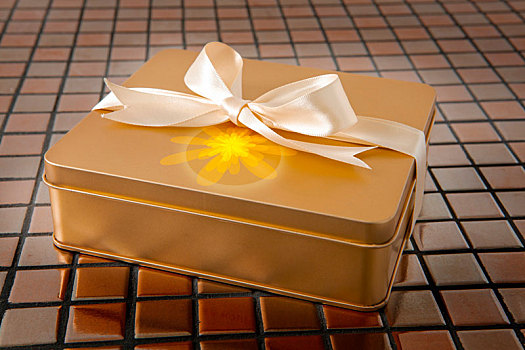 绑上缎带的金色礼盒在磁砖的背景上