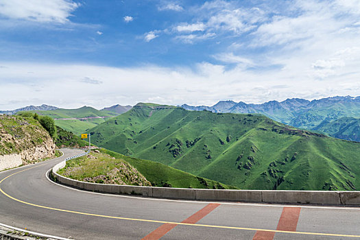 中国新疆夏季蓝天白云下高山森林g217独库公路弯道