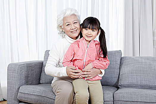 奶奶抱着孙女坐在沙发上