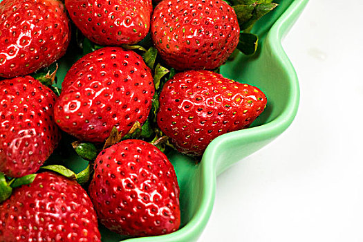 绿色盘子里的多颗新鲜绿叶红色草莓