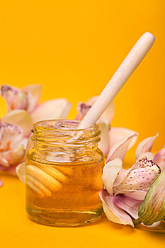 黄色背景下放在桌子上的蜂蜜和鲜花