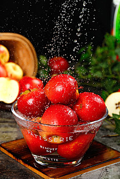 木板上放着一碗樱桃小苹果