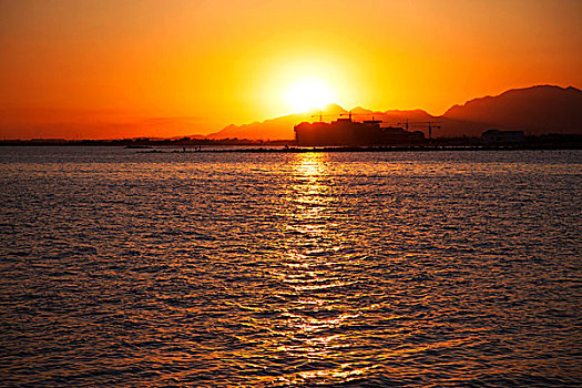 红色夕阳照映下的大海和城市的海岸线