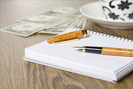 钢笔,桌子,笔记本,美元货币,杯碟
