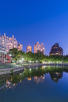 中国北京朝阳公园湖边的树林建筑夜景