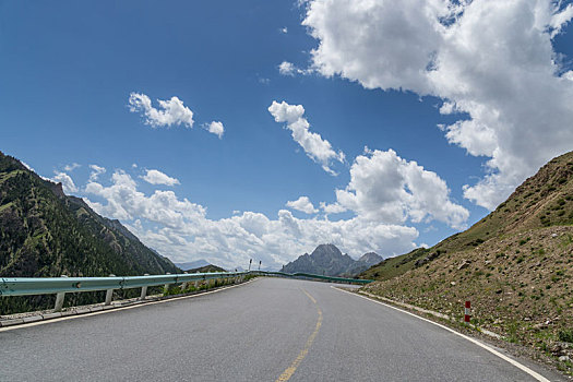 中国新疆夏季蓝天白云下高山森林g217独库公路弯道