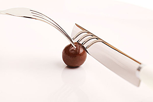 在白色盘子里用银色刀叉切开圆形棕色巧克力