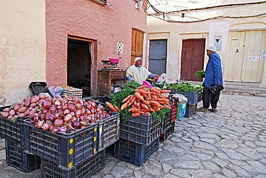 algeria,ben,isguen,man,buying,vegetables,from,a,market,stall