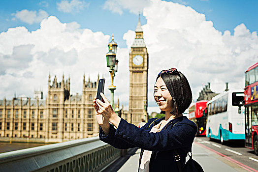 微笑,女人,黑发,照相,智能手机,站立,威斯敏斯特桥,上方,泰晤士河,伦敦,议会大厦,大本钟,背景