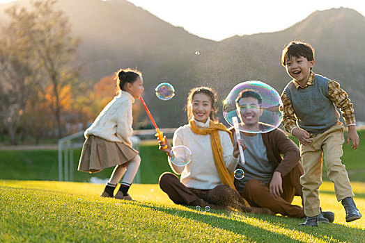 年轻夫妻和孩子们在草地上玩泡泡