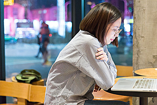 年轻的女性在咖啡馆中工作,坐在笔记本电脑前